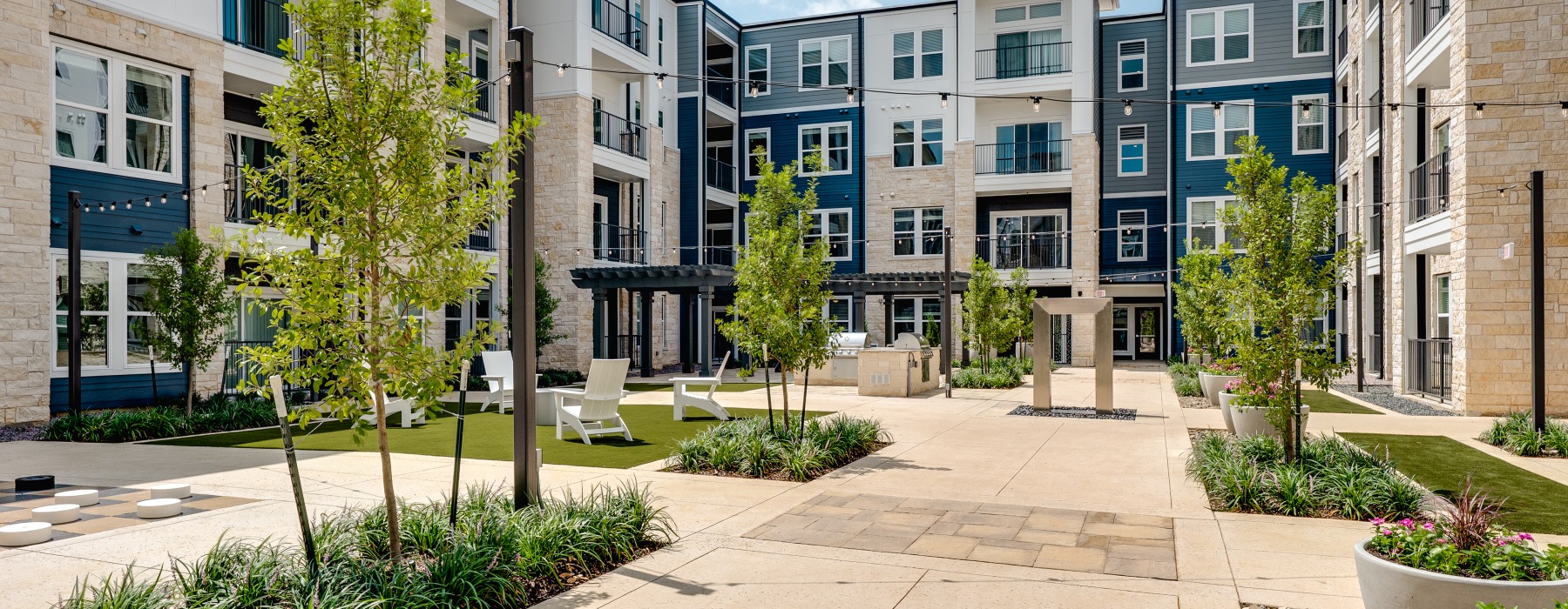Courtyard area with areas of landscaping with monkey grass and green trees